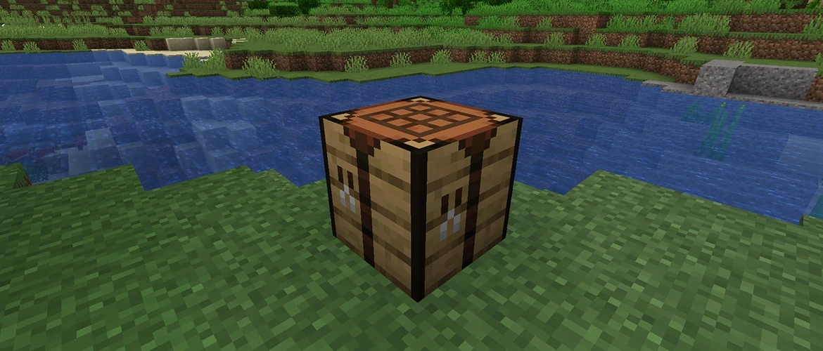 Minecraftの川辺の草地に置かれた作業台と、向こう岸の地形